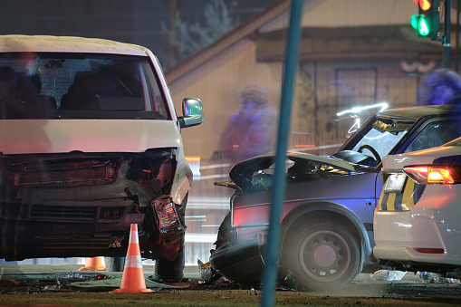 Cars crashed heavily in road accident after collision on city street at night. Road safety and insurance concept.