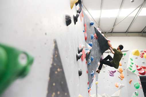 Professional Male Climber On Climbing Wall In Indoor Activity Centre