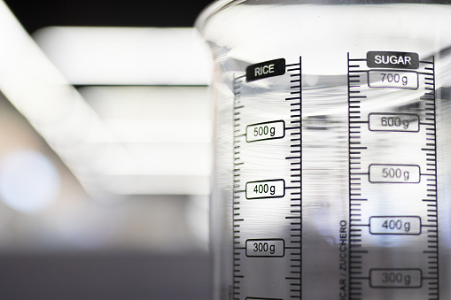 Close-up on a transparent measuring jug with scales for rice and sugar, selective soft focus.