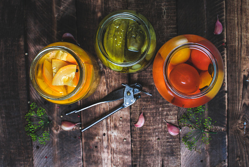 Glass jars of pickled fresh, homemade vegetables on a wooden background. Top view. Stock of food