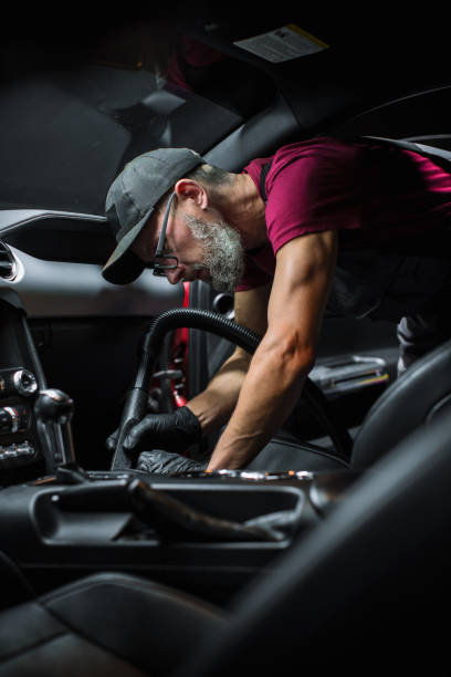 specialist professional car cleaning and detailing company vacuum cleaning an ecological perforated black faux leather interior in a modern sportscar. worker cleaning every little seam on the car seat - car cleaning inside of indoors imagens e fotografias de stock