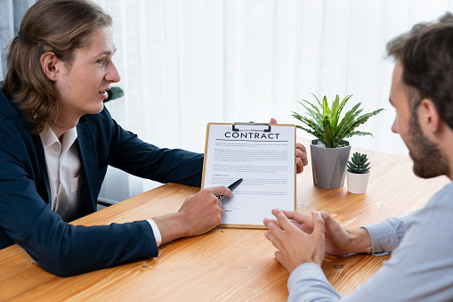 Businessman carefully reviewing contract document for corporate partnership. Client reading agreement deal and terms on meeting table for professional business decision. Entity