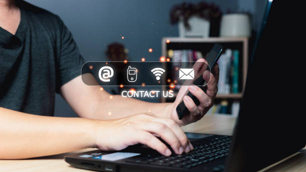 istock Businessman using smartphone and computer laptop with virtual screen contact icons(address,phone,wifi,email),Contact us and Customer support hotline people connect. 1489459000