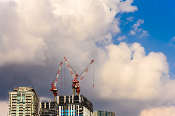 construction crane of high rise building construction site with cloudy overcast sky background.
