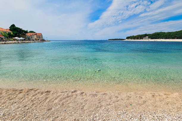 Beautiful pebble beach with crystal clear water in medieval croatian town in Northern Dalmatia