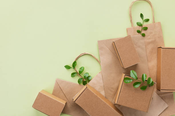 istock Eco, zero waste and plastic free minimal concept from sprout with green leaves growing from recycled cardboard box and craft packages top view. 1489462010
