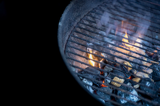 A lit barbecue pit with flames and coals ready for cooking.