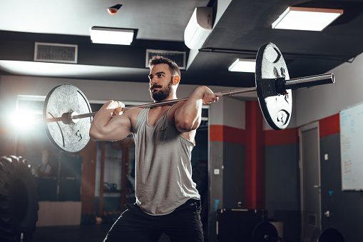 Young muscular man lifting a barbell at the gym.