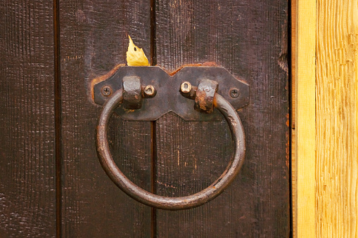 Door Knocker. Brown wooden door with metal knocker