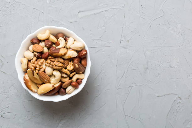 istock mixed nuts in bowl. Mix of various nuts on colored background. pistachios, cashews, walnuts, hazelnuts, peanuts and brazil nuts 1489464547