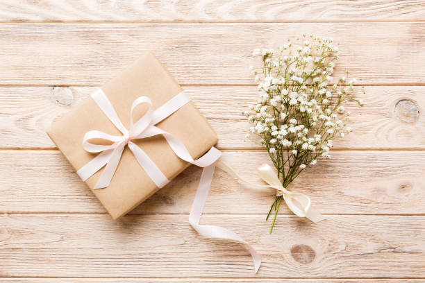 istock Gift or present box and flower gypsophila on light table top view. Greeting card. Flat lay style with copy space 1489464561