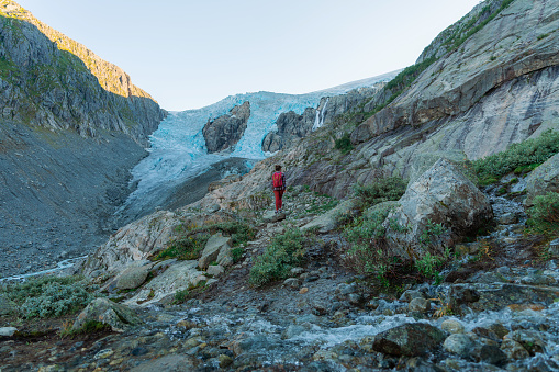 Young Caucasisan woman hiking on the background of Jostedalsbreen  glacier