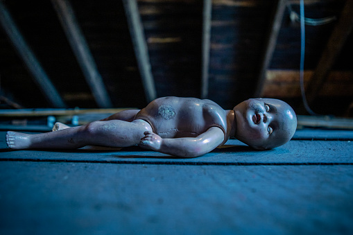 An old creepy doll lost in a dirty old attic.