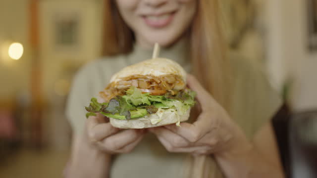 Woman grab the Vegetarian Hamburger and show the layer of it.