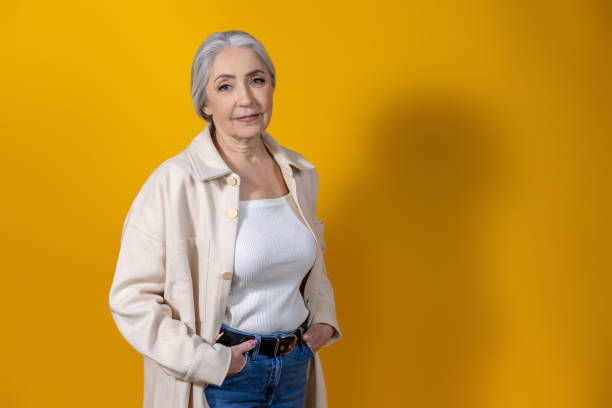 istock Good-looking woman in beige standing on yellow background 1489469532