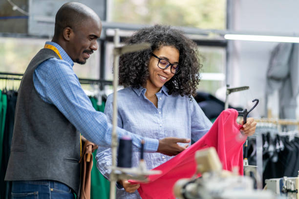 istock Young african-american colleagues in a tailor studio having discussion, holding a textile product. 1489472832