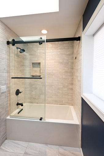 A contemporary modern bathroom design. featuring a glass enclosed bathtub
