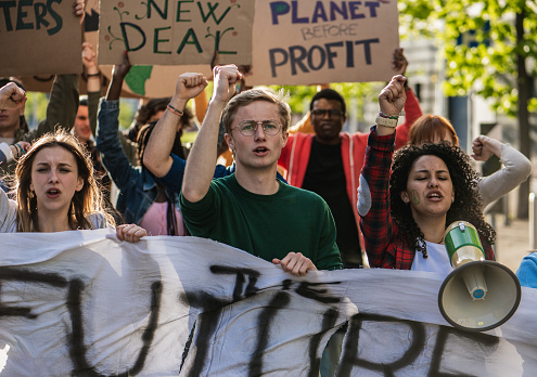 Young environmentalists in protest carry billboards of protest, young students sing choruses of dissent