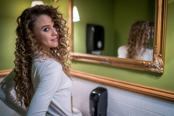 Young woman looking in the mirror at home