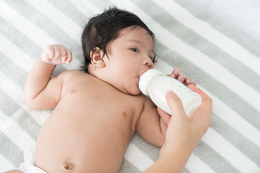Asian newborn baby eating milk from nipples from mother hand. Mother feeding her infant with milk bottle