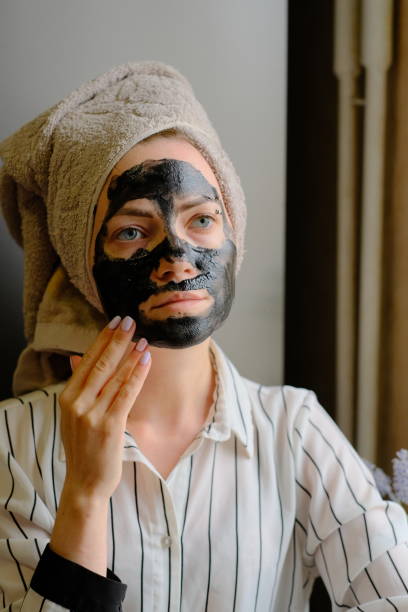 istock Woman applying black cosmetic mask on her face 1489477208