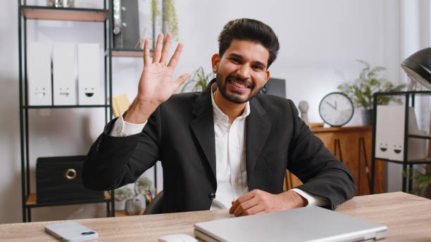 istock Businessman working on laptop smiling friendly at camera and waving hands gesturing hello at office 1489477703