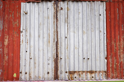 Old wall of corrugated iron with bolts, nuts and repairs in the central part of Sri Lanka