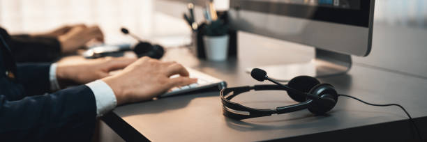 istock Panorama focus headset on call center workspace desk with blur operator. Prodigy 1489481250