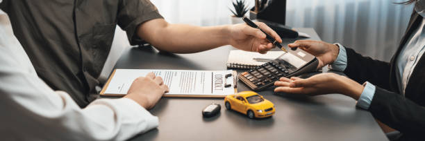 Car dealer calculate interest rate and costs of car loan. Prodigy Car dealer calculate interest rate and costs of car loan with calculator, explaining details to customer on term and agreement in dealership office, offering financial and insurance service. Prodigy car finance stock pictures, royalty-free photos & images