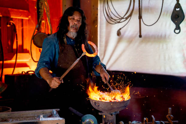 istock Senior man hold tools that hold horseshoe during process of strike the iron in room with fire in stove. 1489491217