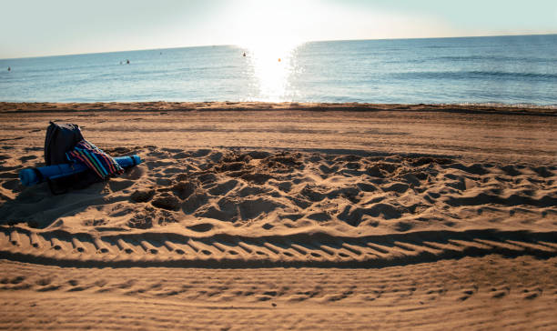 Swimwear, towel and backpack on empty sand beach. Summer Holiday swimming in the morning