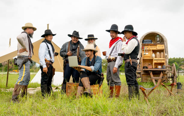 un gruppo di uomini cowboy rimane sul campo e si diverte a usare il laptop per lavorare o comunicare con altre persone. - cowboy desire west poster foto e immagini stock