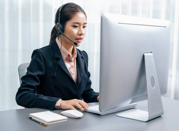 istock Enthusiastic asian call center with headset and microphone working on her laptop 1489492757