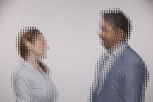 Man and woman discussing behind checkered glass