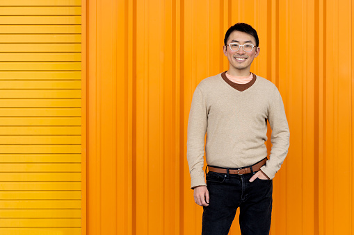 Portrait of an Asian man using cellphone against a colorful background