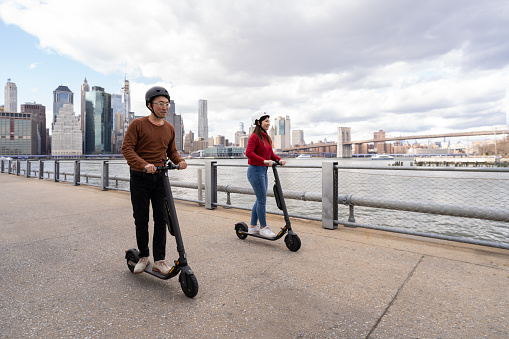 Asian friends using electric scooter in NYC