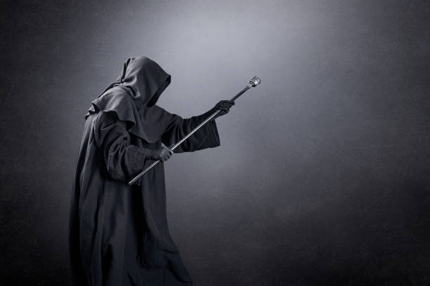 Wizard with hooded cape and magic staff over dark misty background