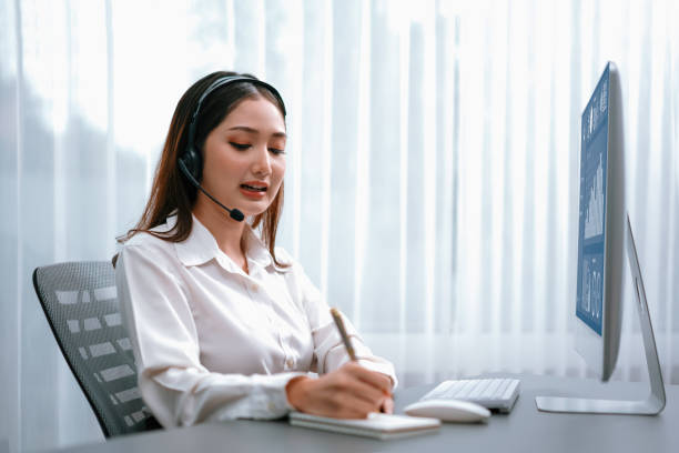 istock Enthusiastic asian call center with headset and microphone working on her laptop 1489498249
