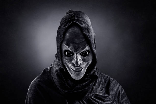 Scary figure with hooded cloak in the dark stock photo