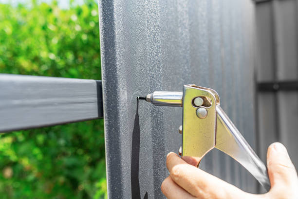 istock A worker puts rivets into a profiled sheet on a fence. 1489502023