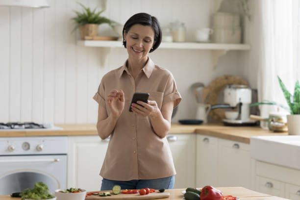 istock Cheerful happy mature chef woman using mobile phone 1489504346