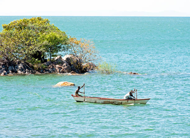 Fishermen rowing canoe, Lake Malawi, Malawi, Africa. Malawi, the landlocked country in southeastern Africa, is a country of highlands split by the Great Rift Valley and the huge Lake Malawi, whose southern end is within Lake Malawi National Park and several other parks are now habitat for diverse wildlife from colorful fish to the Big Five. Cape Maclear is known for its beach resorts, whilst several islands offer rest and recreation.