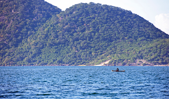 Solitary fisherman rowing canoe, Lake Malawi, Malawi, Africa. Malawi, the landlocked country in southeastern Africa, is a country of highlands split by the Great Rift Valley and the huge Lake Malawi, whose southern end is within Lake Malawi National Park and several other parks are now habitat for diverse wildlife from colorful fish to the Big Five. Cape Maclear is known for its beach resorts, whilst several islands offer rest and recreation.