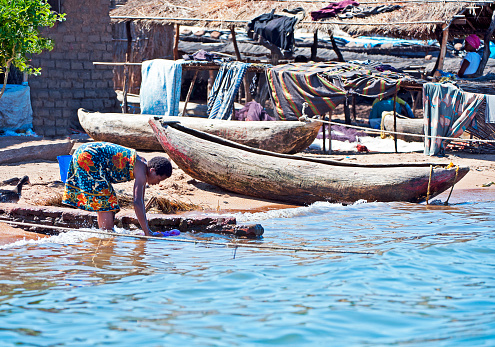 Washing clothes alongside dugout canoes on the lakeshore, Masaka Fishing Village, Lake Malawi, Malawi, Africa. Malawi, the landlocked country in southeastern Africa, is a country of highlands split by the Great Rift Valley and the huge Lake Malawi, whose southern end is within Lake Malawi National Park and several other parks are now habitat for diverse wildlife from colorful fish to the Big Five. Cape Maclear is known for its beach resorts, whilst several islands offer rest and recreation.