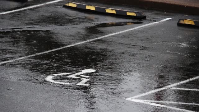 Rain Falling On Parking Lot With Handicap Symbol