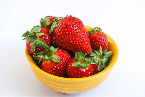 Fresh raw organic strawberries in glass bowl plate on white background. Macro