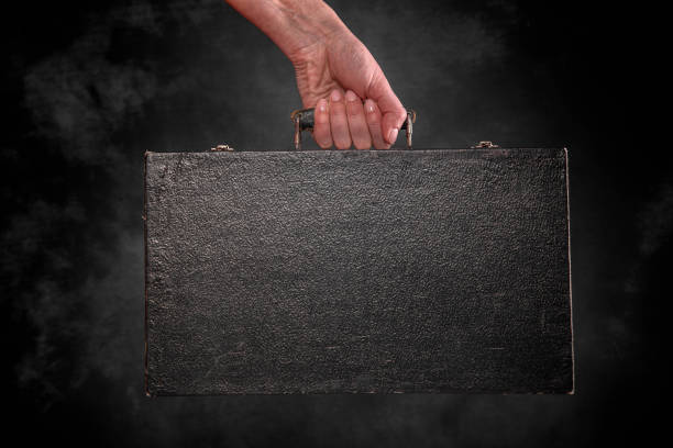 istock Old suitcase in a female hand on a dark background. 1489514500