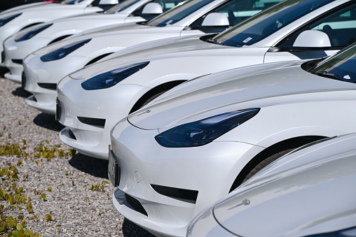 Berlin, Germany - 11 May, 2023: White electric Tesla Model 3 cars in a row on a public parking. This model is one of the most popular electric cars in the world.
