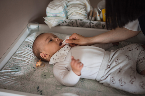 Close-up of a caucasian newborn baby holding life-support hoses and cables tight in his had with wrist nametag while sleeping in a hospital bed.