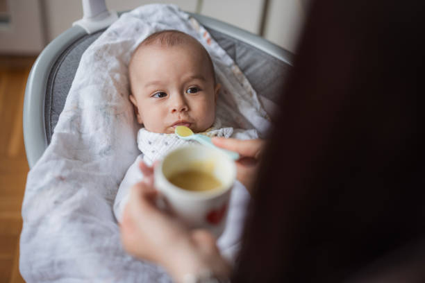 Baby resting in baby bouncer and eating smashed veggies